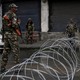 Indian security forces stand near concertina wire.