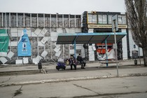 Two people sit at a bench in a Donbas town.