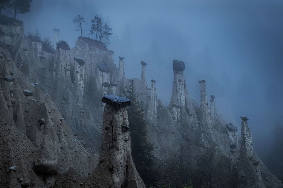 An eroded rock formation, looking like pillars of stone capped by dark rocks.