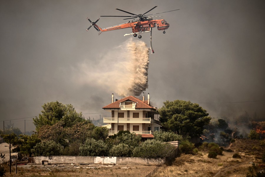 A firefighting helicopter drops water over a house.