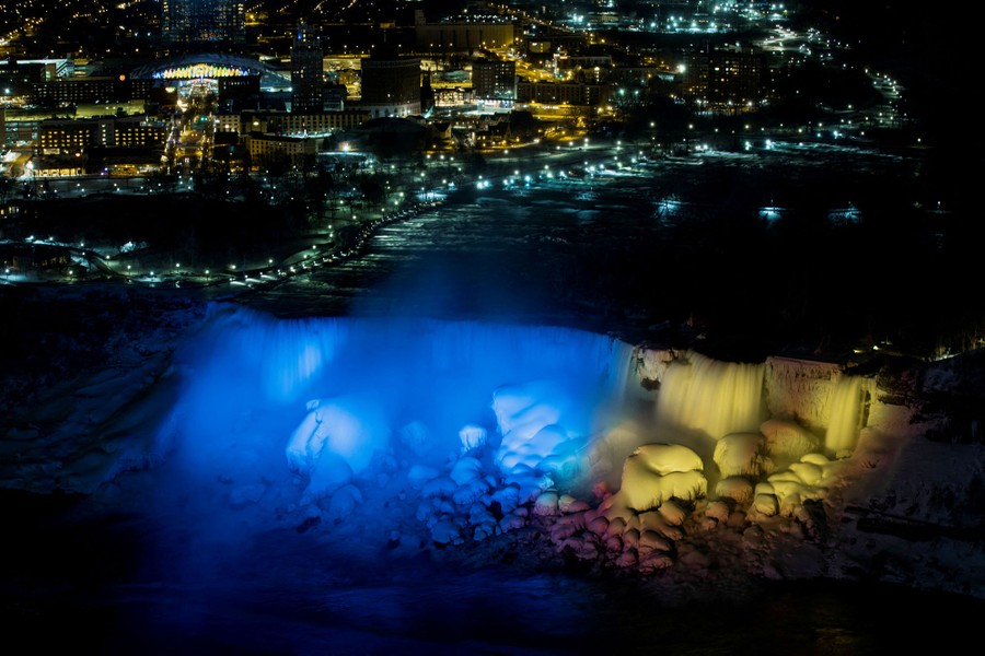 A night of view of Niagara Falls, from above, illuminated in blue and yellow—the colors of the Ukrainian flag