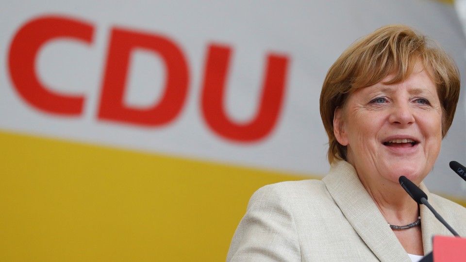 German Chancellor Angela Merkel gives a speech with her party's sign in the background.