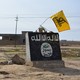 A flag of the Shiite militant group Saraya al-Khorasani flutters over a mural depicting the emblem of the Islamic State in Al-Alam, a village in Iraq.