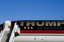 Trump waves standing next to his private plane that reads: TRUMP