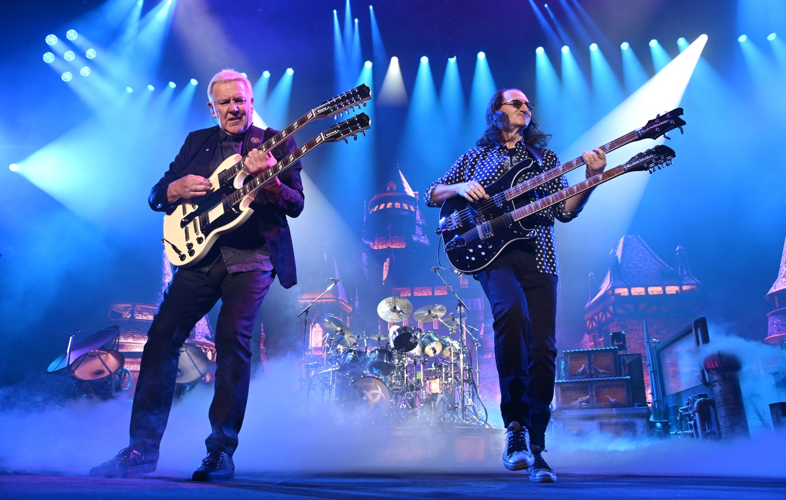 Alex Lifeson and Geddy Lee of Rush play guitars, performing on stage.