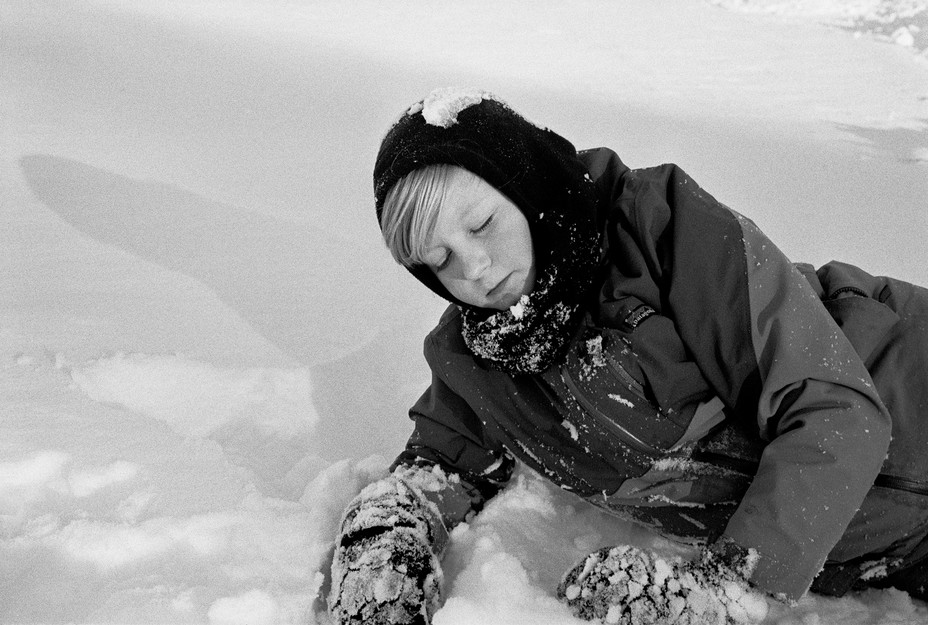 BW image of a boy laying in the snow
