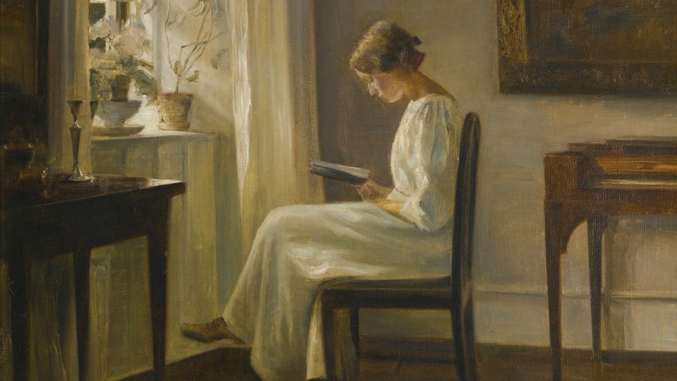 A woman reads next to a window