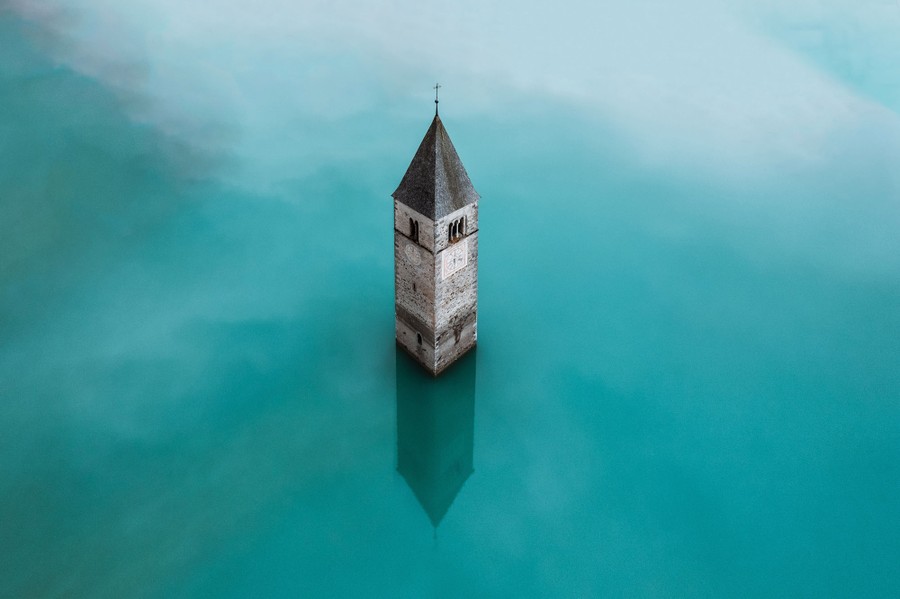 An old church tower stands in the middle of a reservoir.