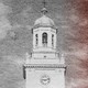 Black and white image of a college building with red color seeping in from the right