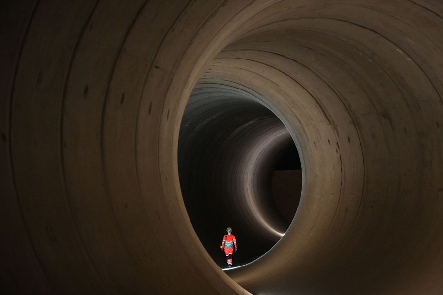 An engineer walks inside a large concrete tunnel.