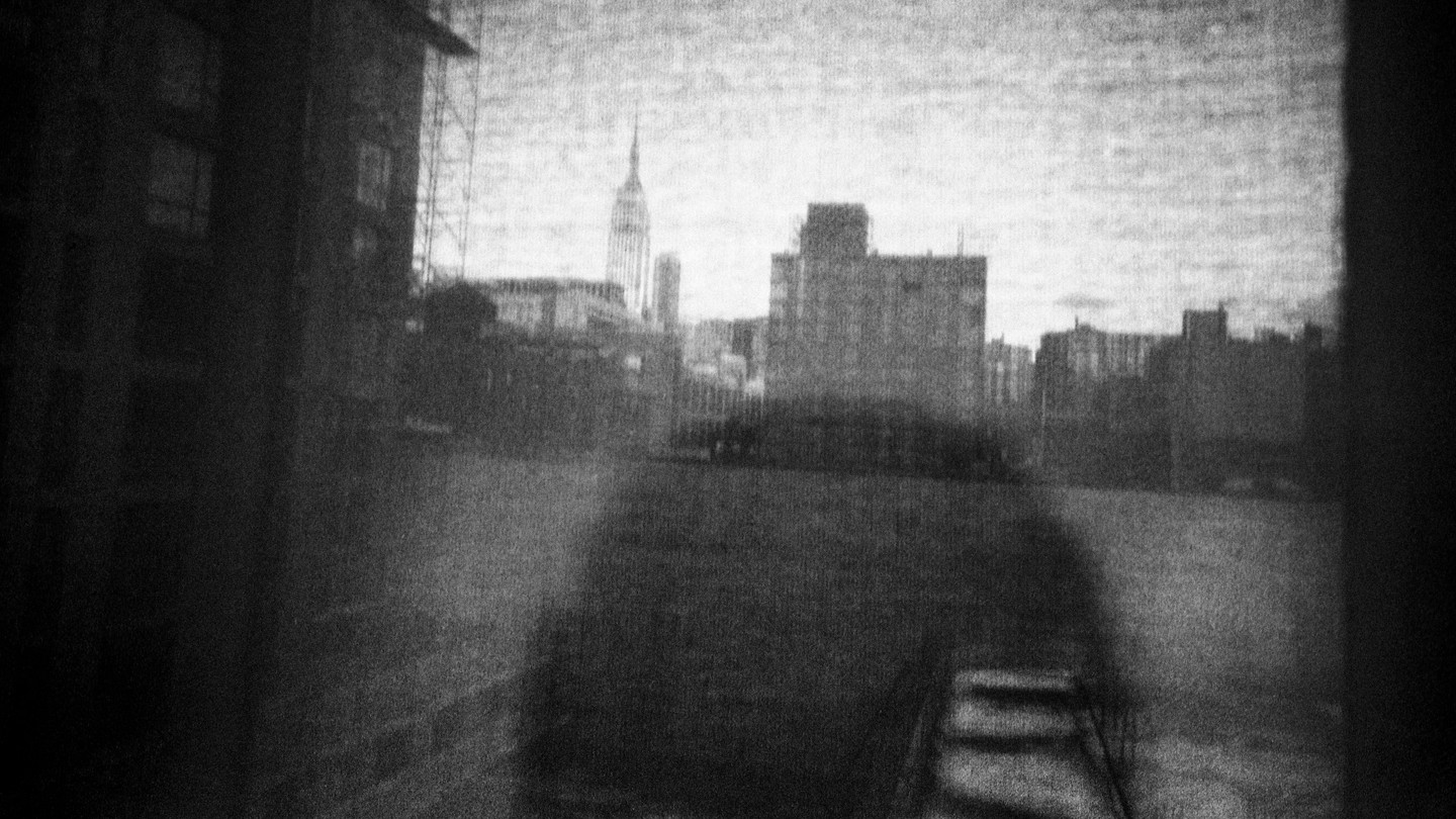 Shadow figure looking over black-and-white city scene