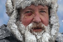 A close view of a bearded man wearing snow gear, his whiskers covered in ice
