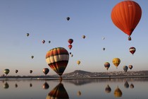 Hot-air balloons and their reflections along a coastline 