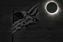 A flag waves in the dark, with a full eclipse in the background