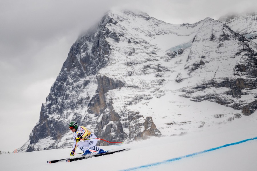 A skier races past a rocky mountain face.