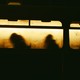 Yellowed windows of a train with 4 silhouettes visible