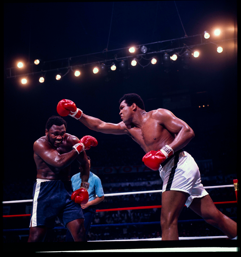 color photo of Ali and Frazier boxing, with Ali's right arm reaching as Frazier dodges
