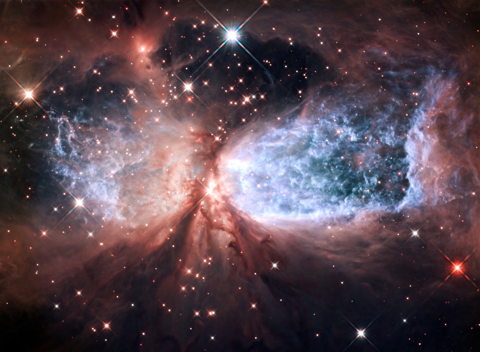 Gas, dust, and starlight create a glowing explosion. It was vaguely shaped like an hourglass, lying on its side.