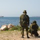 Soldiers point guns at the ocean