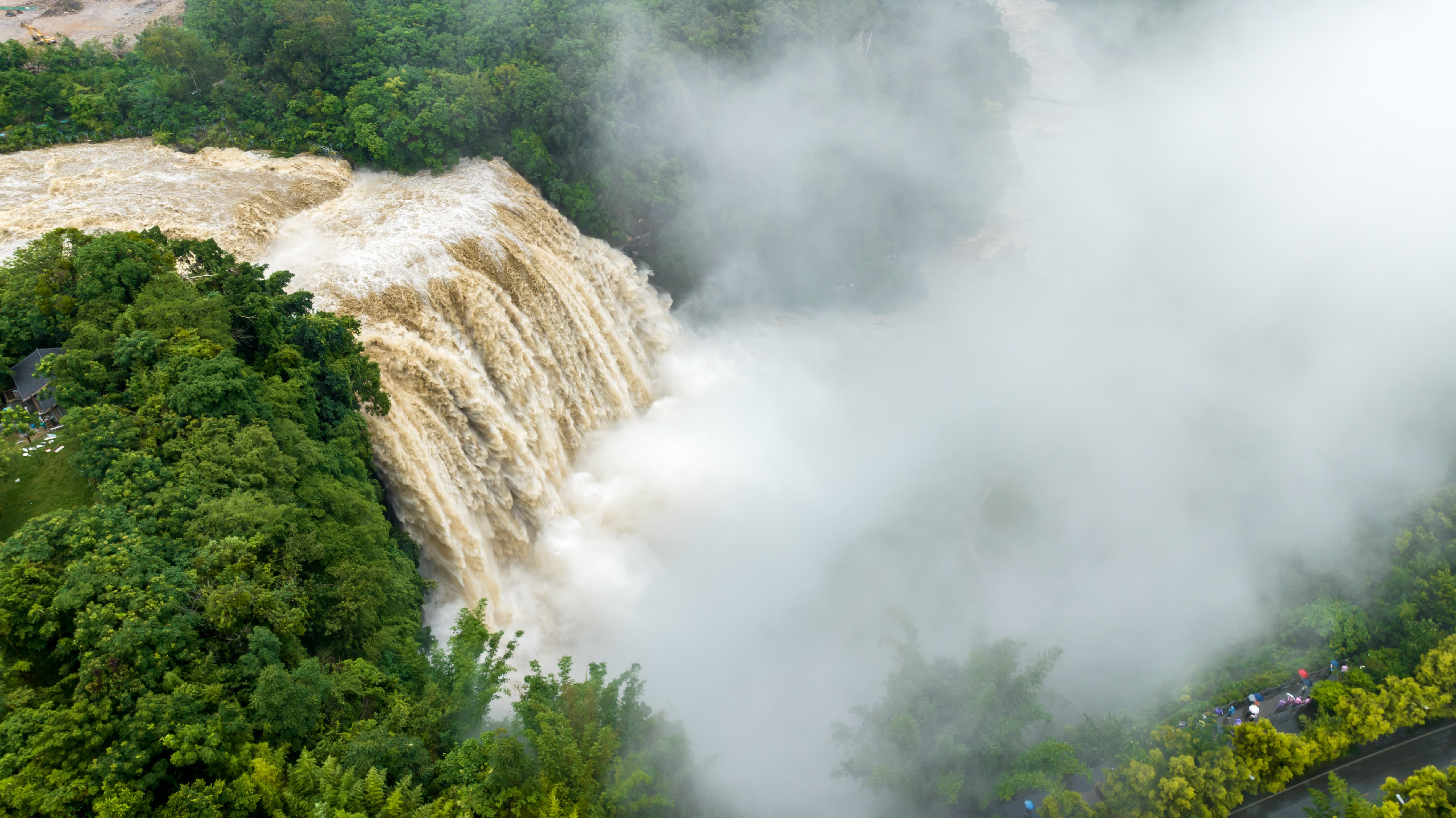 A surging waterfall descends through a forested area.