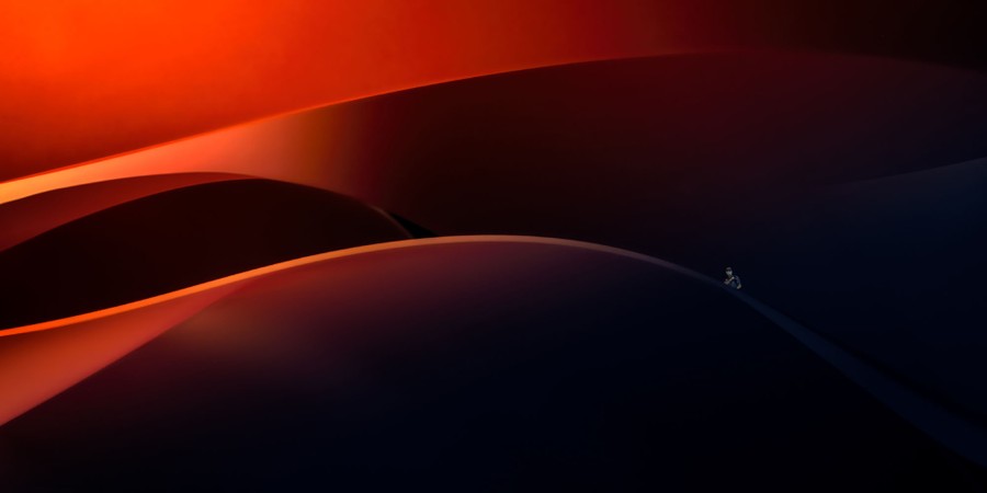 A person stands, looking small among swooping architectural features.