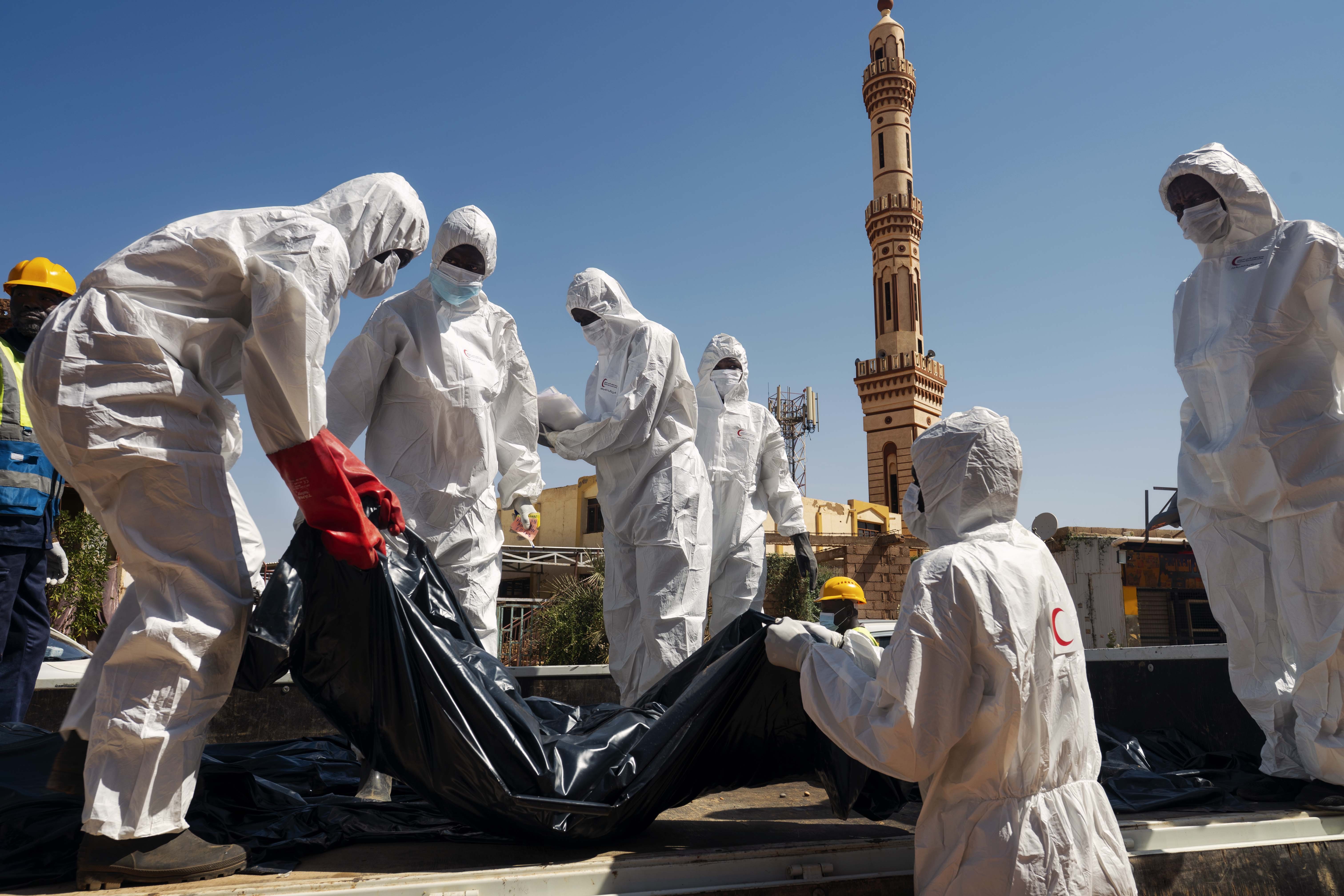 Workers recover a corpse in a body bag
