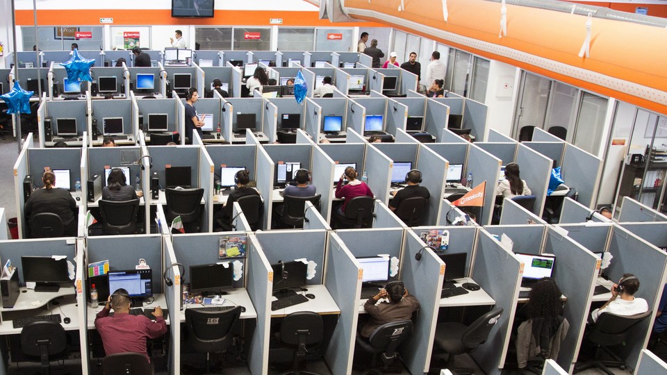 Workers sit at desks in a call center