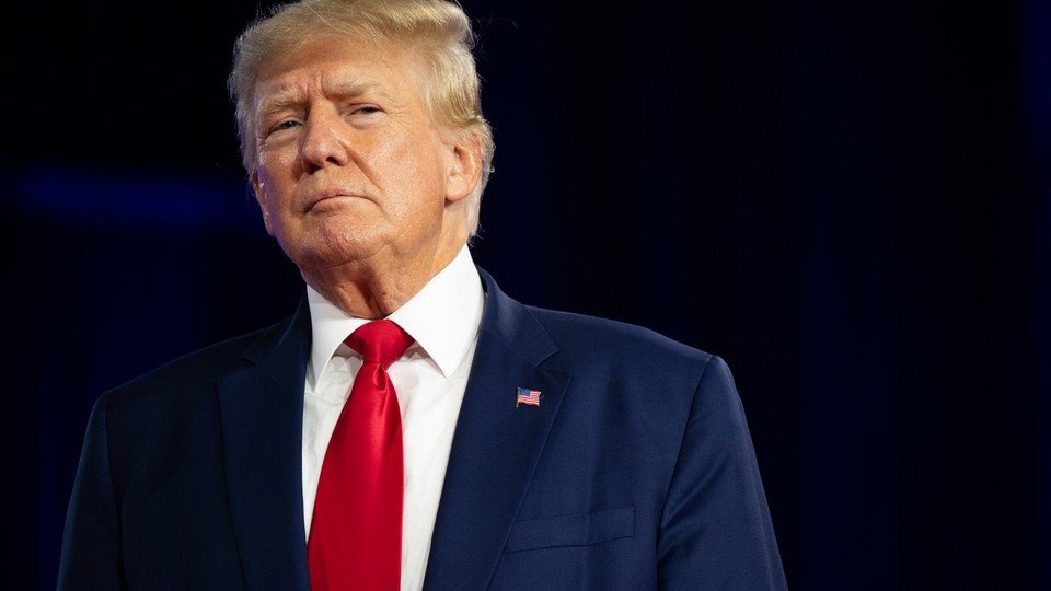 Donald Trump wearing a red tie and American flag pin