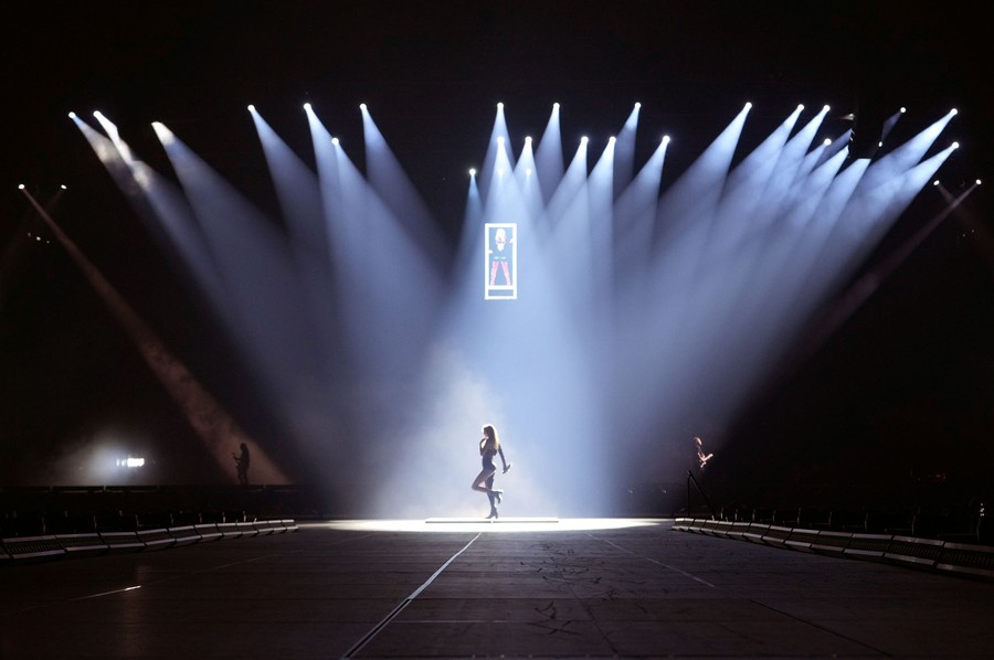 Taylor Swift performs onstage, backlit by spotlights.