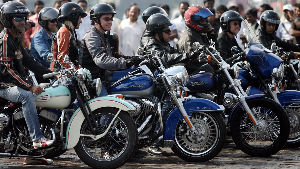 Helmeted riders sit on motorcycles