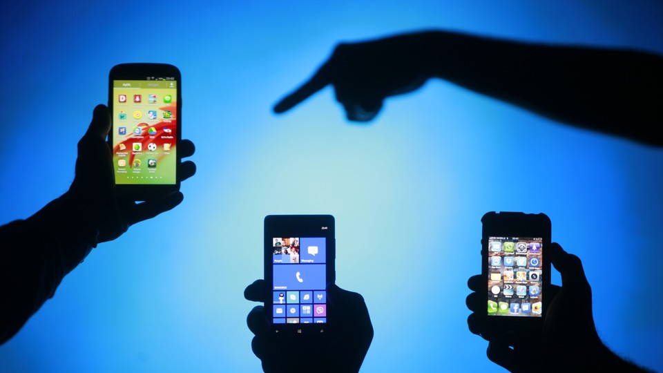 Three silhouettes of hands holding smartphones with silhouette of finger pointing at them on blue background