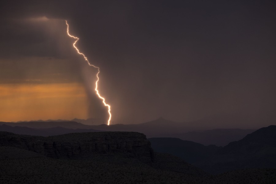 Lightning strikes the land in a broad vista, during a storm.