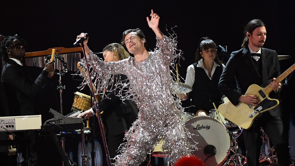 Harry Styles performing in a silver tassled jumpsuit
