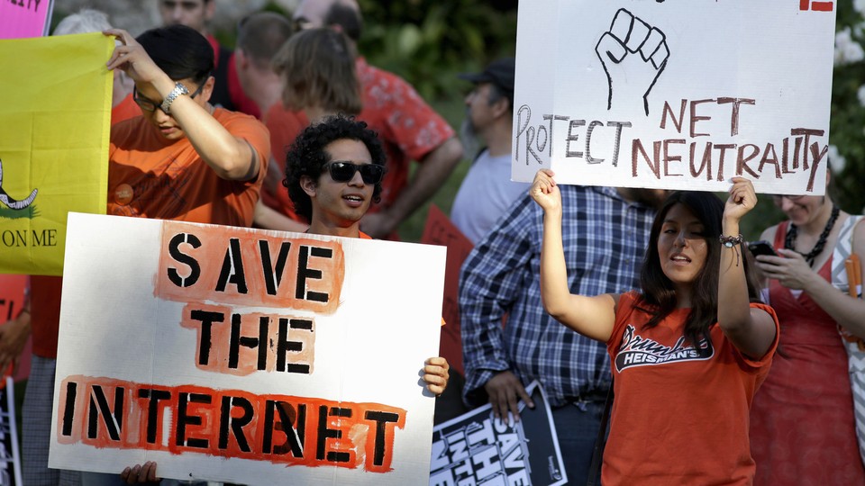Activists hold signs at a rally for network neutrality.