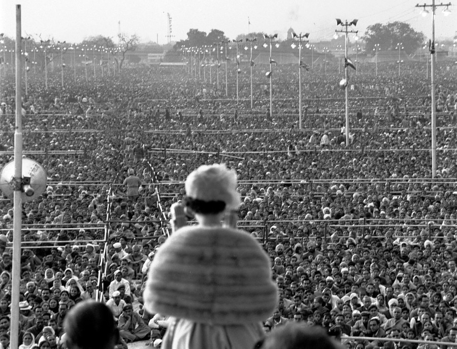 A shot of the Queen from behind, as she addresses an enormous crowd standing before her