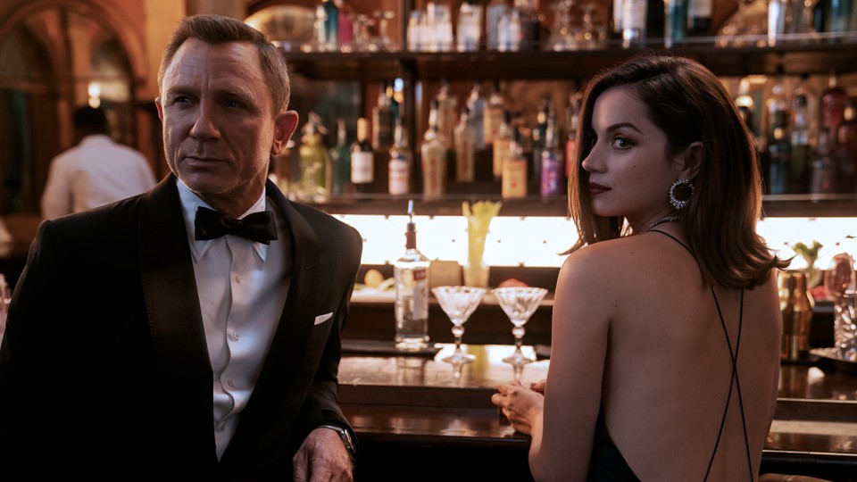 Daniel Craig and Ana de Armas dressed in black cocktail attire at a bar for a scene in 'No Time to Die'
