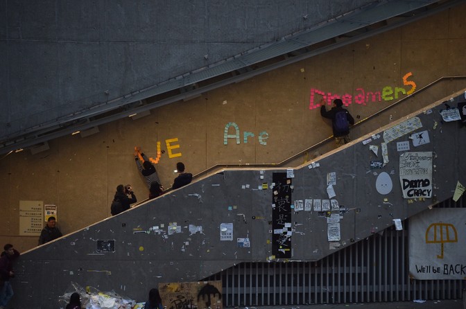 Prodemocracy protesters remove signs placed up during the past two months of protests from the area around the protest camp but leave intact the notice "We are dreamers"