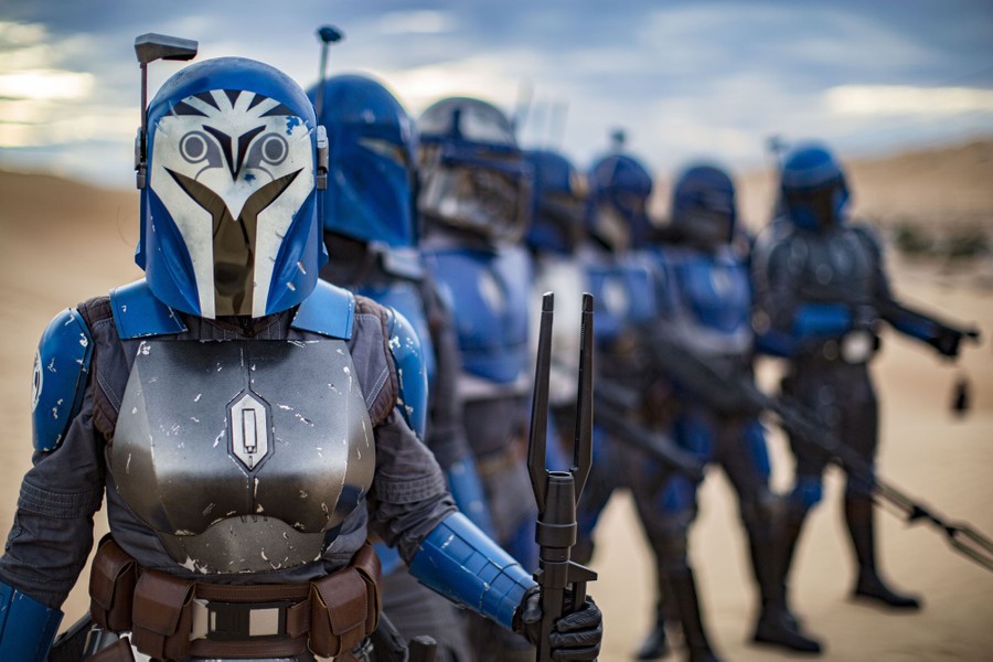 People dressed in Star Wars-themed costumes pose together in a desert.