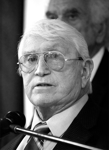 black and white photo of Burl Cain wearing aviators and speaking at a microphone