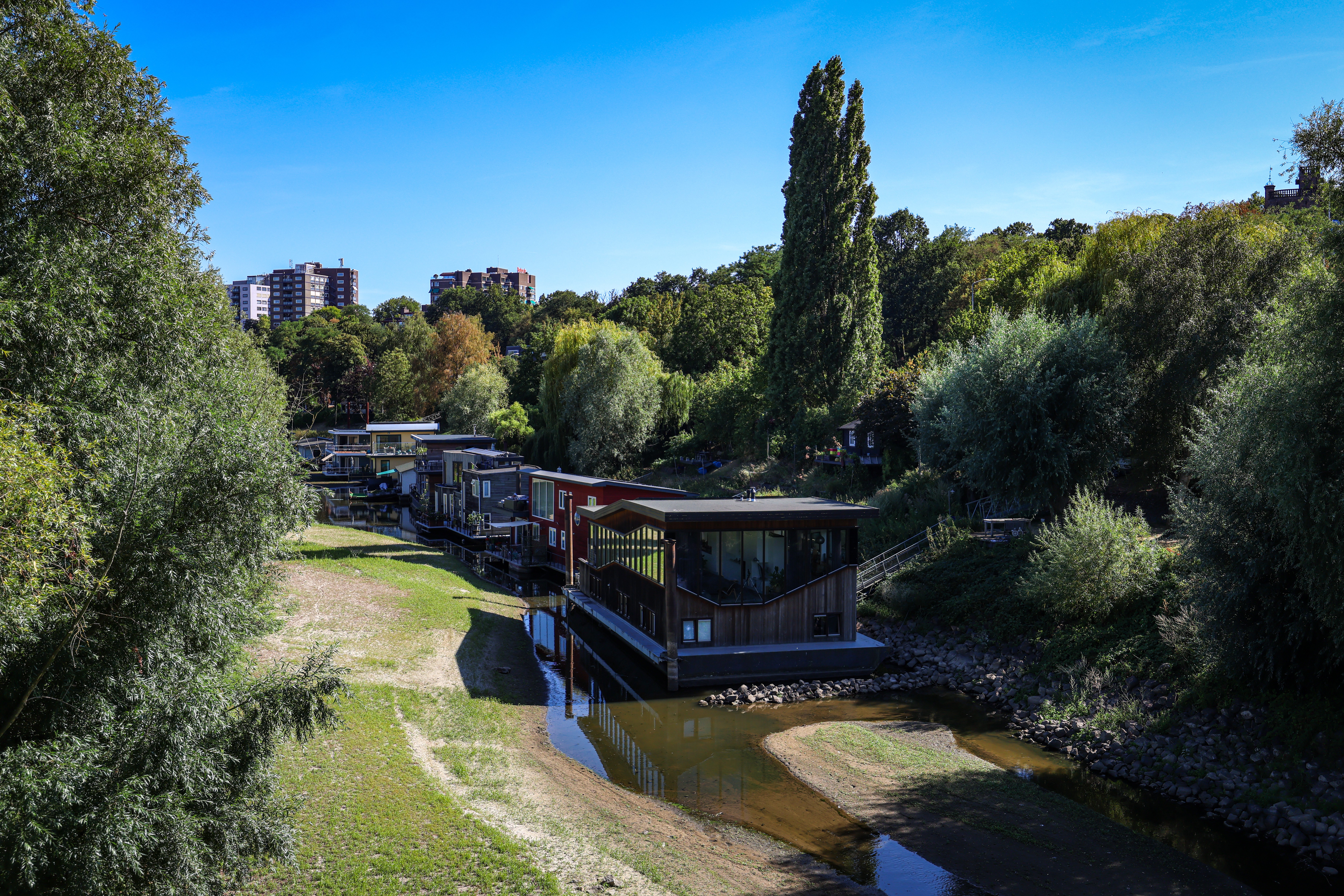 A marina with grounded houseboats, surrounded by exposed riverbed
