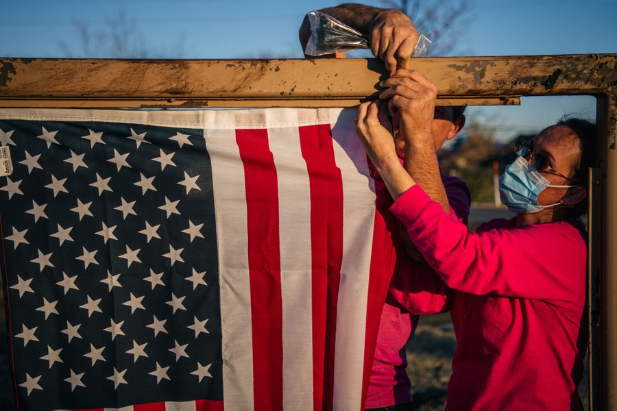 A husband and wife hang an American flag outside a storm-damaged nursing home.