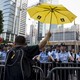 A pro-democracy protester rises a yellow umbrella, the symbol of the Occupy Central movement, in front of a line of police officers.