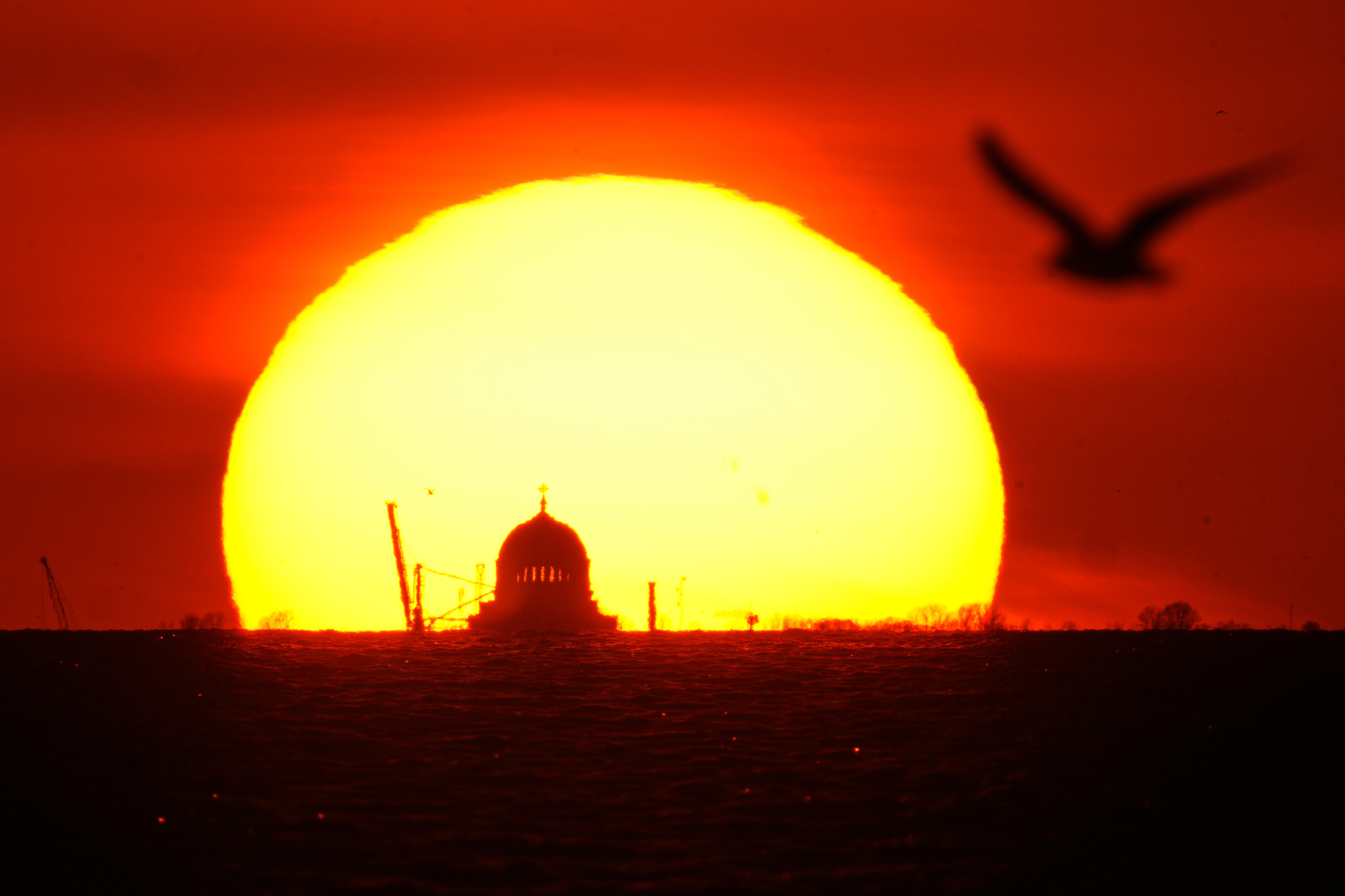 The sun sets behind a distant cathedral.