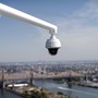 A security camera hangs from the roof of the Secretariat Building at the United Nations headquarters with the East River and Queensboro Bridge in the background in New York City.