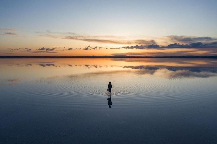 A person stands in an expanse of shallow, flat water