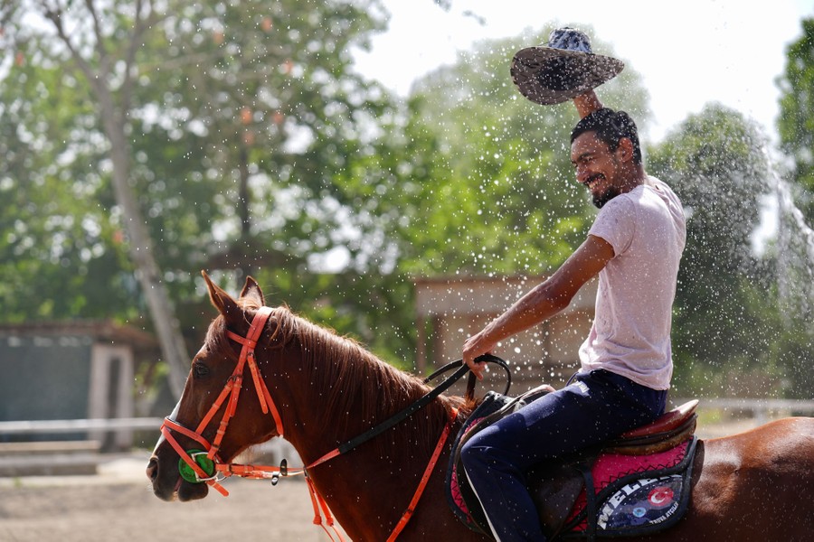 A man rides on a horse as they are splashed with water.