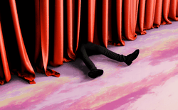 Legs are seen next to a red curtain