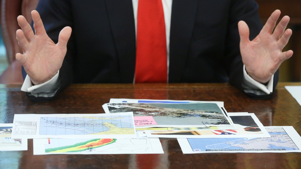 President Trump looks at hurricane-prediction documents.