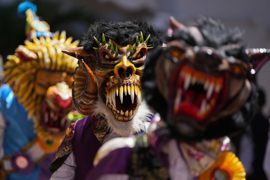 Several performers dance while wearing elaborate devil masks.