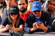 Bernie Sanders supporters look down at their phones during a rally.